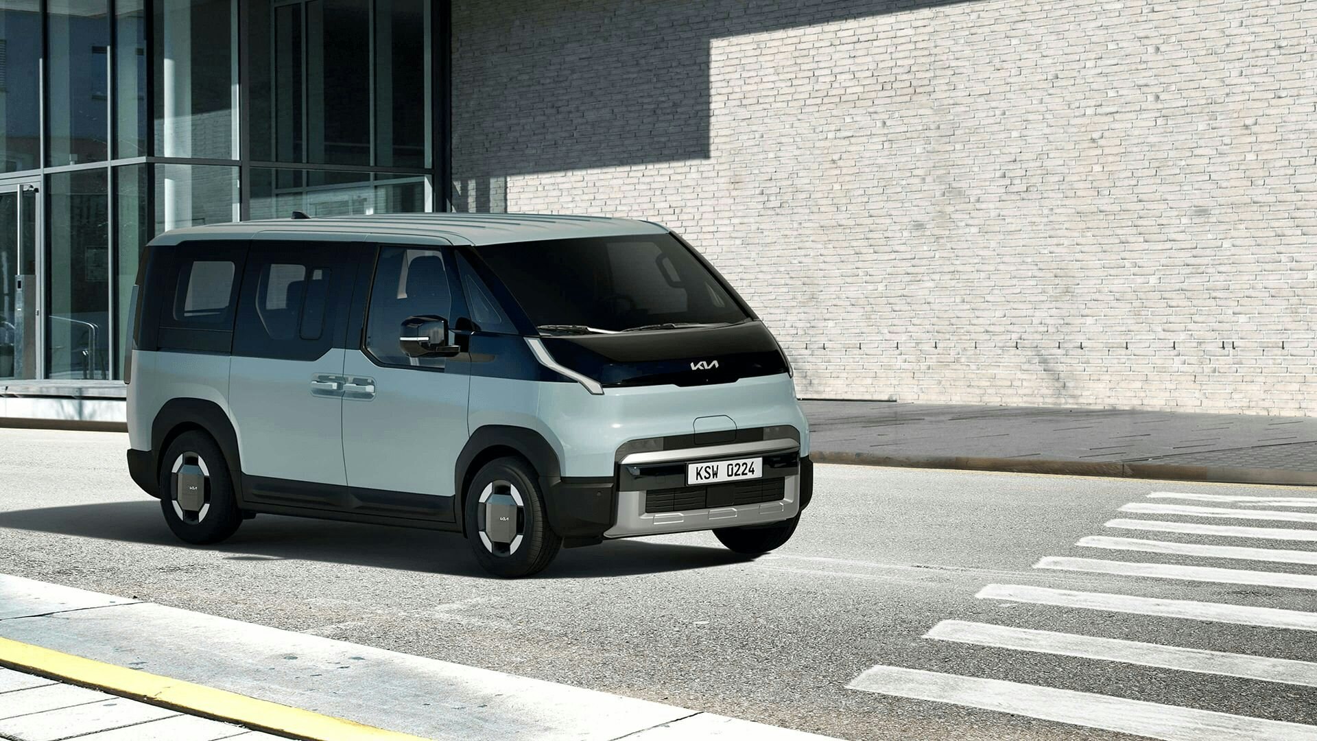 Frontansicht des Kia PV5 Passenger bei der Fahrt durch eine städtische Küstenregion